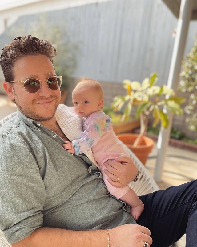 Trevor Einhorn in a grey shirt with his niece in a pink baby dress.